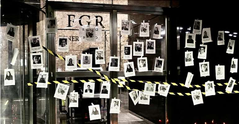 Photos of slain Mexican journalists are placed on the symbolically closed doors of the attorney general’s office in Mexico City during a vigil in memory of Fredid Román Román, a journalist shot to death in his car in Chilpancingo on August 22, 2022. (Reut