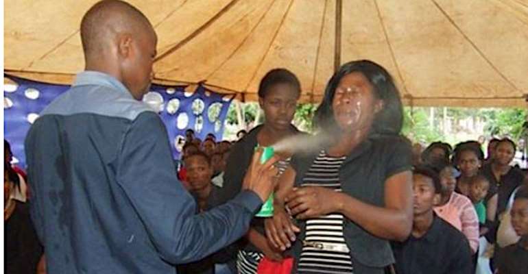 PASTOR SPRAYING INSECTICIDE ON MEMBERS