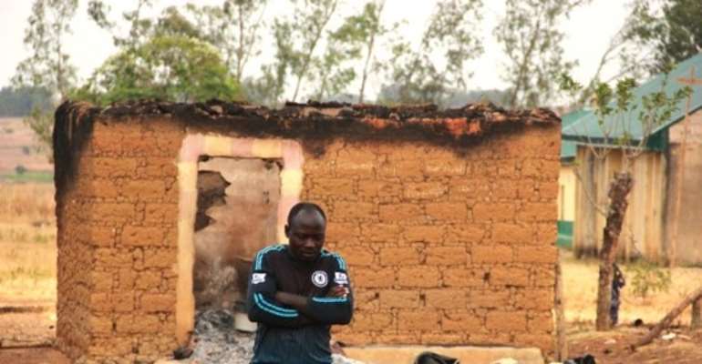 A man stands in front of a burnt-out house in Kwatas village, Bokkos LGA, after an attack on 24 November 2022. Credit: Masara Kim