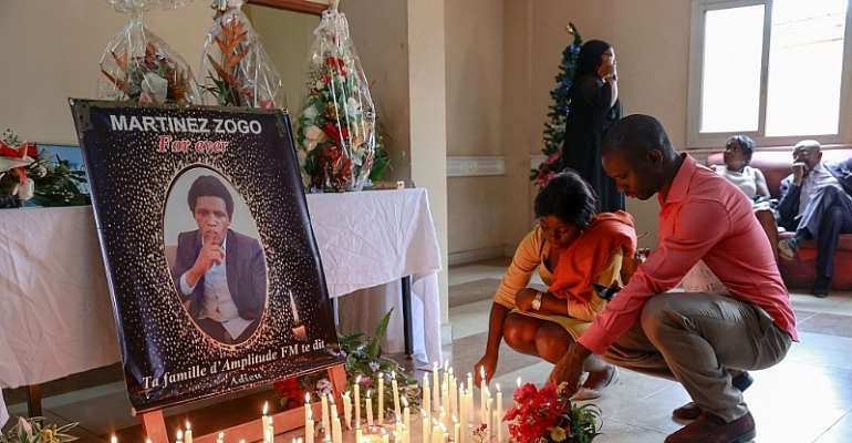 Mourners place candles in front of a portrait of murdered Cameroonian journalist Martinez Zogo, at his outlet Radio Amplitude FM, in YaoundÃ©, on January 23, 2023. (AFP/Daniel Beloumou Olomo)