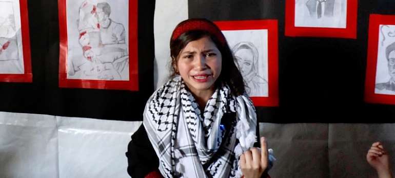 Fatima Al-Za'anin, a displaced Palestinian girl from Beit Hanoun (Gaza), speaks about her drawings in an art exhibition organized by UNRWA in Gaza City as part of its mental health and psychosocial support services. Photo: UN NEWS
   