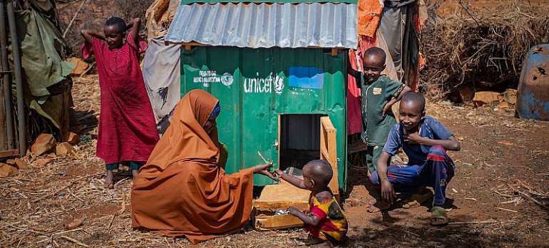 UNICEF/Said Fadhaye: A family poses next to a chicken house provided by UNICEF, in Barwaaqo Camp, Baidoa, Somalia