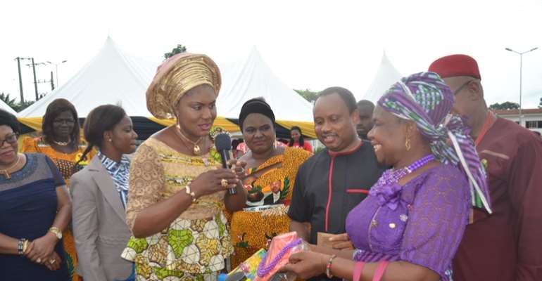 (L-R): Wife of the Governor of Anambra State, Chief (Mrs.) Ebelechukwu Obiano handing over empowerment items to a beneficiary. She is flanked by Special Adviser on Youth Empowerment and Executive Director ANSACA, Dr. Onyeka Ibezim, and His Royal Highness,