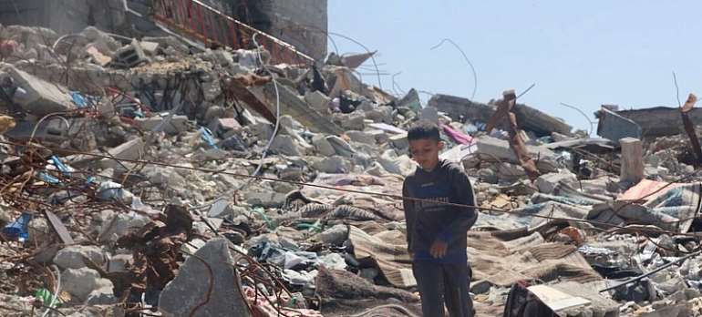 UN News: A child walking among the rubble in the city of Gaza