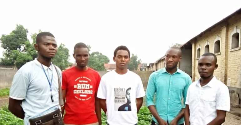 Journalist Chilassy Bofumbo (middle) stands with friends following his release and acquittal on July 5, 2022. His shirt has a graphic of his face and says in French, 