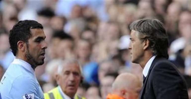 MANCHESTER CITY'S COACH ROBERTO MANCINI (R) SUBSTITUTES CARLOS TEVEZ DURING THEIR ENGLISH PREMIER LEAGUE SOCCER MATCH AGAINST WIGAN ATHLETIC IN MANCHESTER, NORTHERN ENGLAND SEPTEMBER 10, 2011.