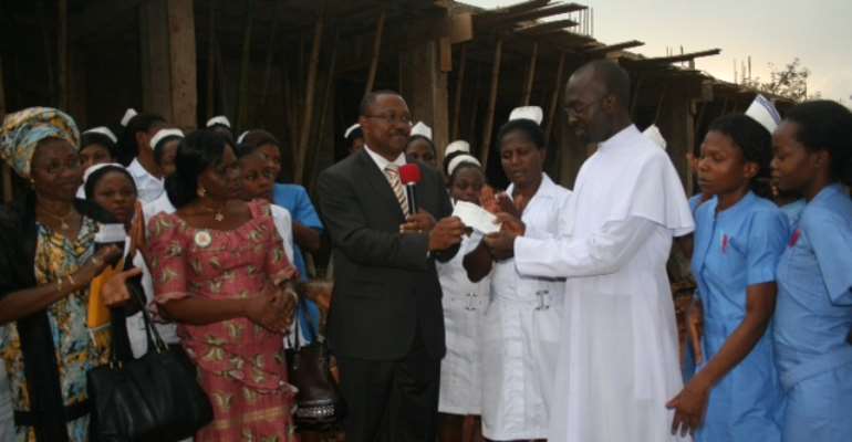 Hospital Manager of Iyienu Hospital, Rev. Ikechukwu Okwuosa (in white), receiving the cheque of 20 million Naira from Gov. Pete
