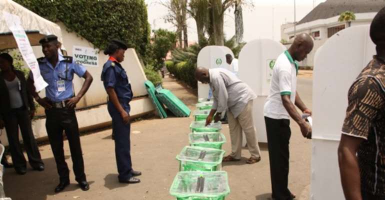 VOTERS CAST THEIR VOTES AS SECURITY AGENTS KEEP WATCH DURING THE PRESIDENTIAL ELECTION IN ABUJA ON APRIL 16, 2011.