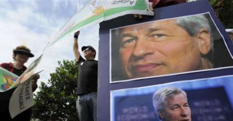 PROTESTORS HOLD SIGNS AND PICTURES OF CEO JAMIE DIMON AS JP MORGAN CHASE & CO CONVENES ITS ANNUAL SHAREHOLDERS MEETING AT THE BANK'S BACK-OFFICE COMPLEX IN TAMPA, FLORIDA, MAY 15, 2012. CREDIT: REUTERS/BRIAN BLANCO
